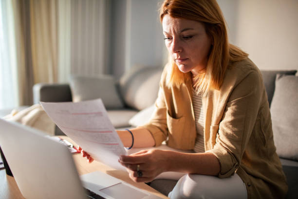 istock Young woman going over her finances at home while using her laptop 1501198187