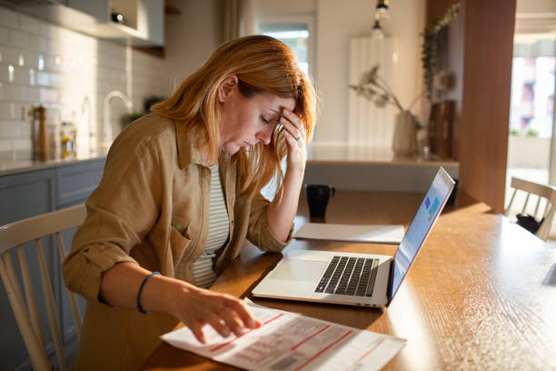 istock Young woman going over her finances at home while using her laptop 1501198275