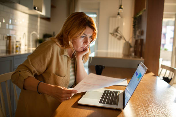 istock Young woman going over her finances at home while using her laptop 1501198423