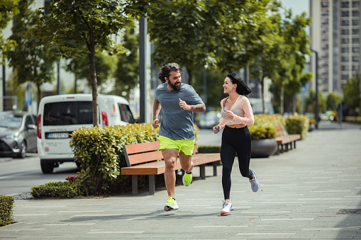 Close up of a young couple jogging and exercising in a city