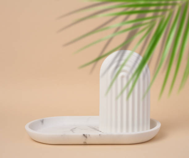 istock Empty oval white marble stand on a beige background and a shadow from palm leaves, a place to display cosmetics and products 1501200261