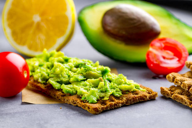 kanapka z awokado z kremem z awokado i chrupkim chlebem żytnim na przekąskę. błonnik, fitness i żywność dietetyczna - avocado lemon snack cracker zdjęcia i obrazy z banku zdjęć