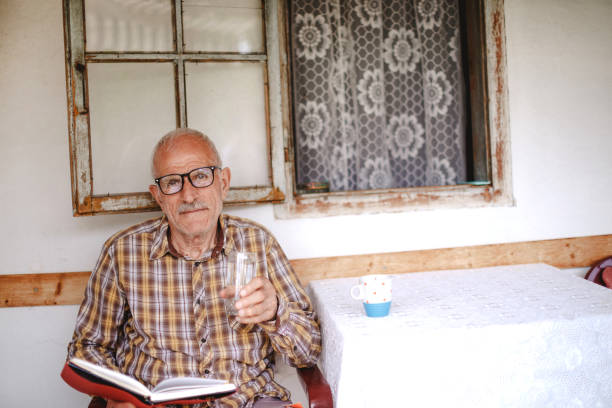 Senior man enjoying retirement days at home and drinking water