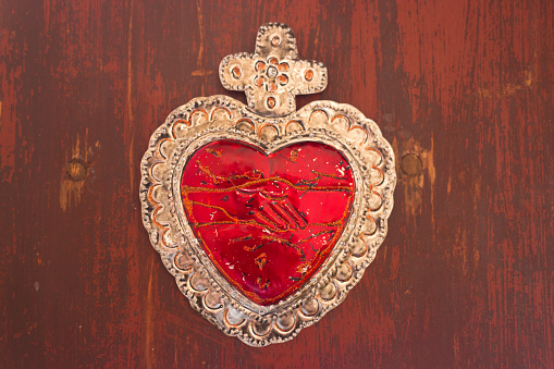 Red Tin Milagros Heart on Weathered Wood Background