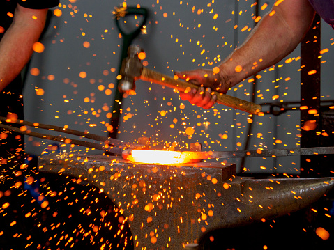 Sparks flying as a farrier hammers a red hot horseshoe into shape on his anvil