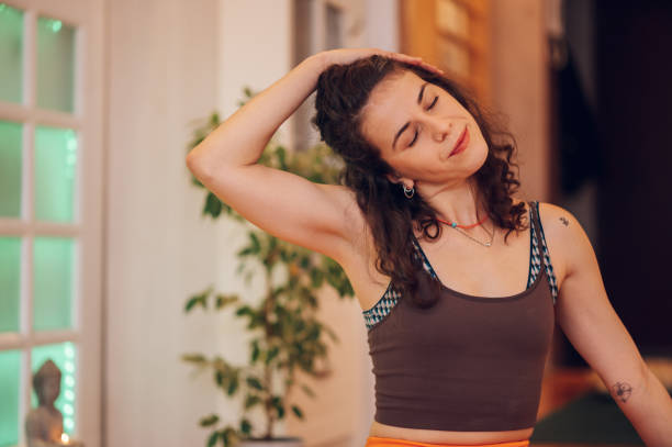 istock Curly girl pushing her head to a side with her hand while stretching the neck. 1501242550