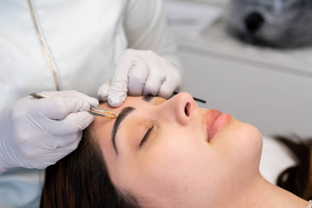 Client getting her eyebrow done by a female aesthetician