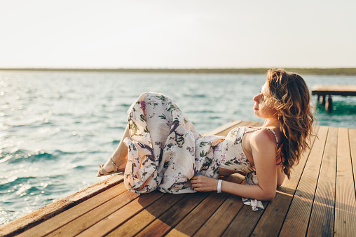 Fashionable woman sitting by the sea. Summer vacation