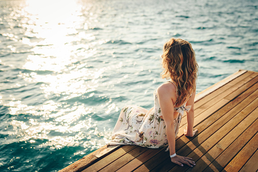 Fashionable woman sitting by the sea. Summer vacation