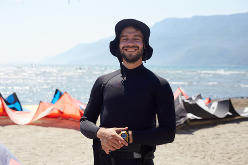Young man completing his preparations for kiteboarding with positive expression on the beach