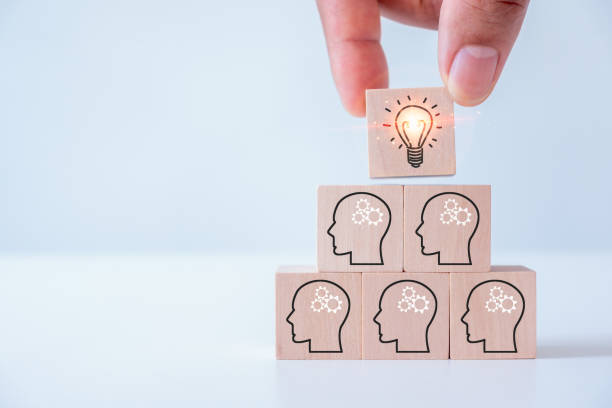 istock teamwork, brainstorming creative idea and innovation. Hand putting over wooden cube block with light bulb icon on many people together having an idea symbolized by icons on cubes. 1501253474