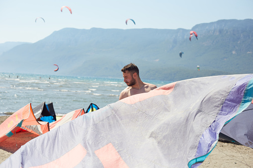 A man is preparing for kiteboard on the beach