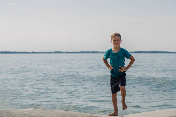 Three kids enjoying sunset at Garda Lake. Kids are sitting on a lake pier.Shot with Nikon D850