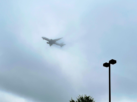 Centreville, Virginia, USA - June 23, 2023: A United Airlines Boeing 777-224(ER) emerges from low storm clouds on short-final approach to Washington Dulles International Airport following a nearly eight-hour flight from Paris, France.