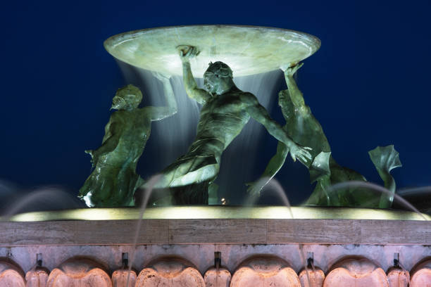 The Tritons’ Fountain is a fountain located just outside the City Gate of Valletta, Malta. It consists of three bronze Tritons holding up a large basin, balanced on a concentric base built out of concrete and clad in travertine slabs. The fountain is one of Malta's most important Modernist landmarks, designed and constructed between 1952 and 1959.Valletta is an administrative unit and the capital of Malta which is an island country in Southern Europe, located in the Mediterranean Sea.