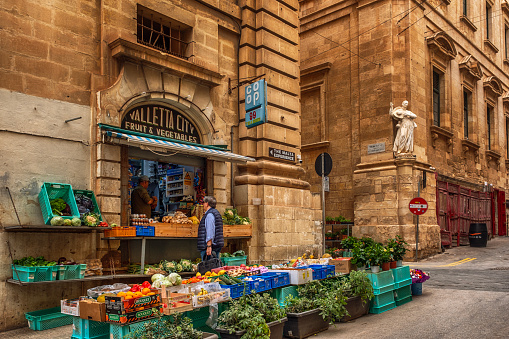 A senior man is shopping from a greengrocery, located on the St. Cristopher Street in Old Town of Valletta, Malta.\nValletta is an administrative unit and the capital of Malta which is an island country in Southern Europe, located in the Mediterranean Sea.