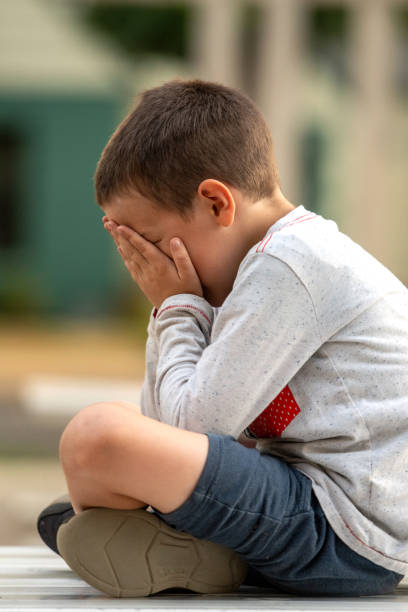istock Crestfallen Crying child boy sitting at the schoolyard covering his face 1501384511