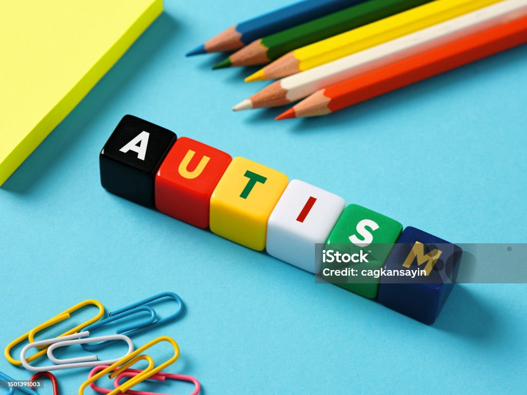 Autism and education concept. Autism spectrum disorder. The word autism on colorful cubes Autism and education concept. Autism spectrum disorder. The word autism on colorful cubes with stationery objects on blue background. Autism Stock Photo