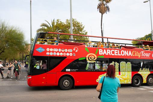 BARCELONA, SPAIN - October 16, 2022. Barcelona city tour bus with people on the street in Barcelona city.