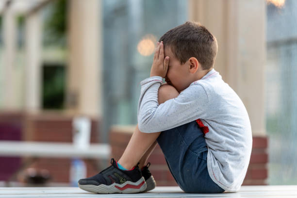 istock Crestfallen Crying child boy sitting at the schoolyard covering his face 1501393013