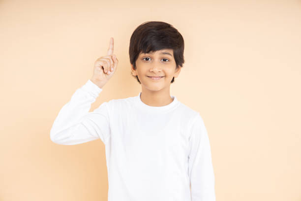 istock Smart little Indian boy wearing plane white t-shirt having an idea expression with smile on his face found a solution isolated on beige studio background. 1501393569