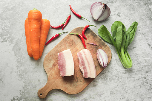 The pork belly and vegetables are placed on the cutting board
