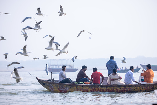 Varanasi, Uttar Pradesh, India - November 2022: Tourists enjoying boat side in the river ganges along with the herd of sea gulls at varanasi.
