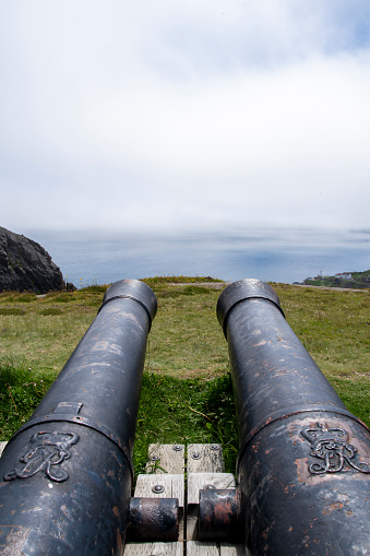 close view of a cannon in an old and Abandoned military coastal bunker in Silleiro Cape with lighthouse in the background, Galicia