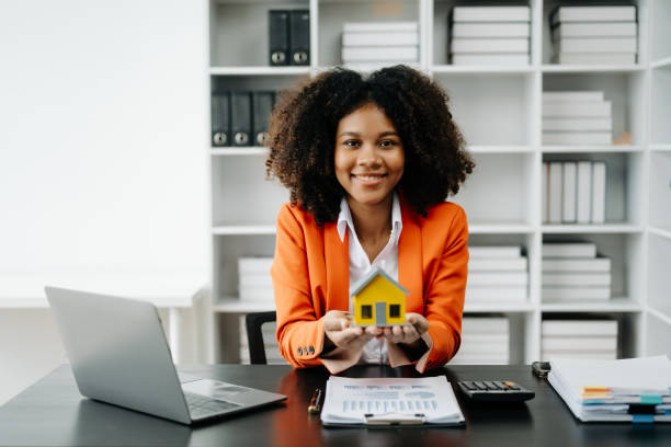 istock Young real estate agent worker working with laptop and tablet at table in office and small house beside it. 1501429407