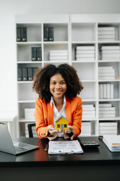 istock Young real estate agent worker working with laptop and tablet at table in office and small house beside it. 1501429417