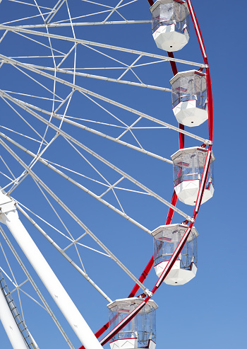 A side on photograph of a red and white colored Ferris wheel located in the waterfront precinct of Darwin Harbor, at Fisherman's Wharf.