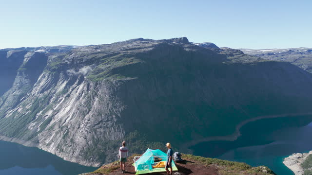 Drone shot: Couple contemplating nature from a tent, wild camping in Norway
