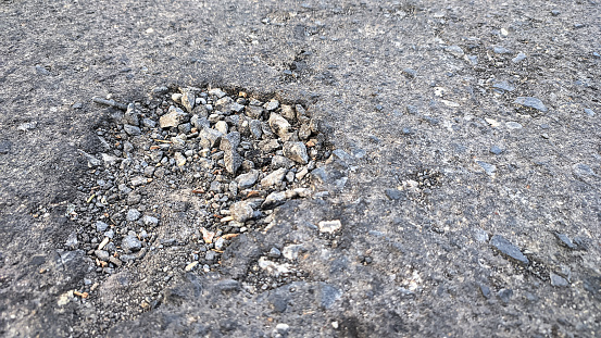 The asphalt road surface is broken and rocky