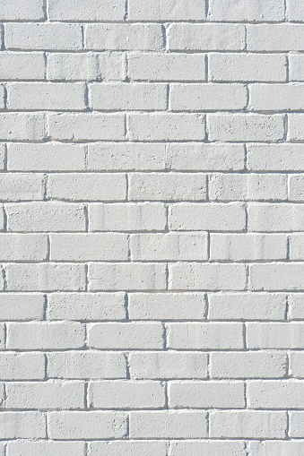 An old white brick wall with an air duct.