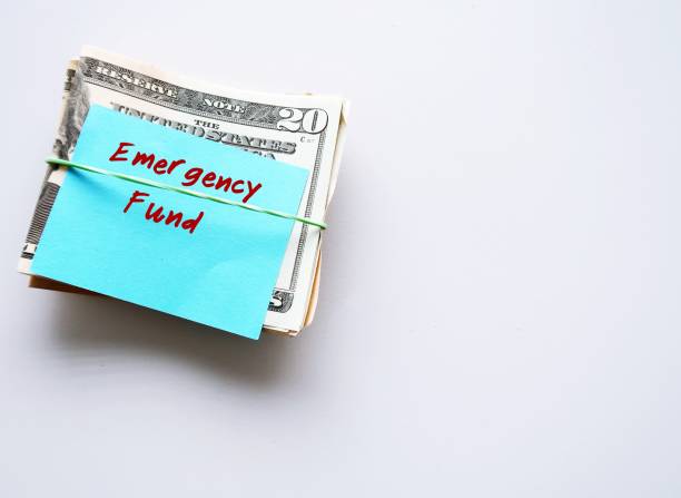 Dollars cash money and paper note with text written EMERGENCY FUND on copy space background - concept of financial planning saving money goal on purpose of rainy day crisis tough time