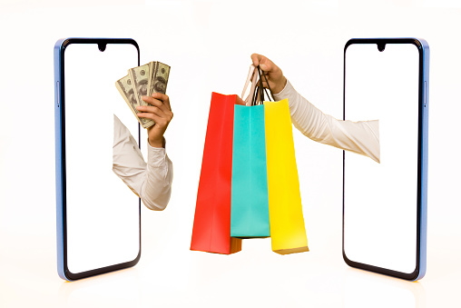 Two Hands outstreched from from different smartphone screen one with dollar bills, the other with shopping bags, white background, isolated. Creative image for delivery service mobile application concept