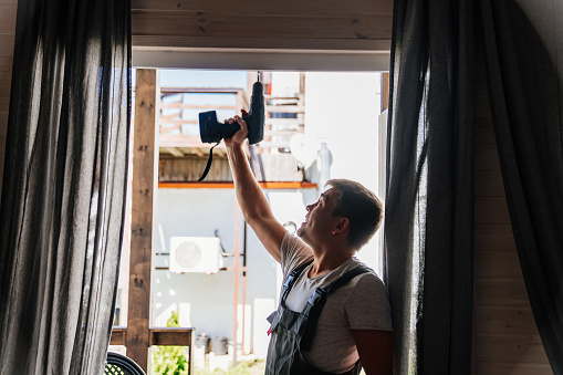 A silhouette of repairman repairs or adjusts window frames or glass doors on the terrace. services of a repairman or installer of furniture and doors.