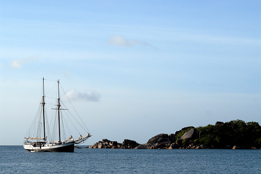 A sailing yacht anchored off of an idyllic island in the Seychelles