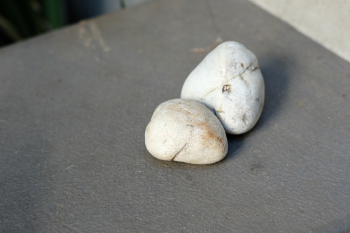 Two small white pebbles on a gray outdoors ledge.