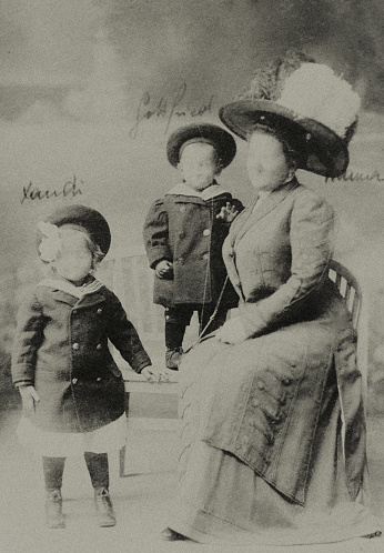 Old portrait photo of a mother with her two small children. The faces have been made unrecognizable. The memories of the persons and their life stories are destroyed.