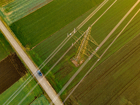 Aerial view of electricity pylon and electric power transmission lines on rural agricultural field
