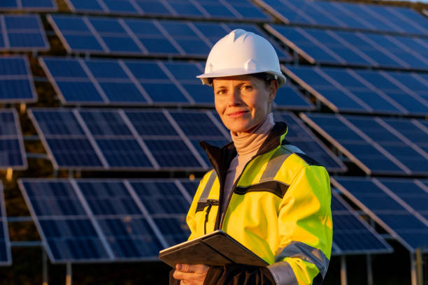 portrait of female engineer holding digital tablet in front of solar panels - solar panel engineer solar power station solar energy imagens e fotografias de stock