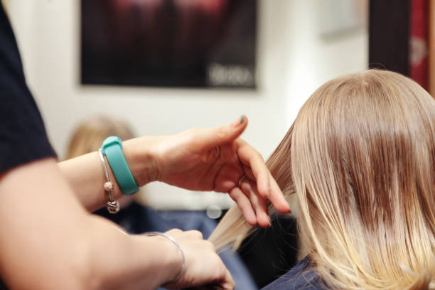 Close up of hairdresser make fashionable hairstyle for cute little blonde girl in barbershop. Hair salon, barber woman makeup hairdo for baby in barber shop. Hair care beauty concept. Copy text space el primer plano de la peluquería hace un peinado de moda para la linda niña rubia en la barbería. peluquería, peinado de maquillaje de mujer barbera para bebé en peluquería. concepto de belleza para el cuidado del cabello. copiar espacio de texto