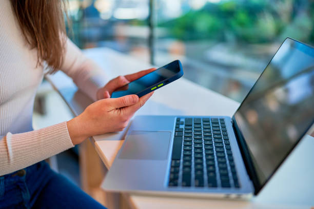 istock Woman freelancer using phone and laptop while remote working online at cafe 1501681659
