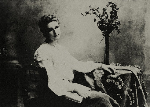 Old portrait photo of a woman. The face have been made unrecognizable. The memory of the person and her life story are destroyed.