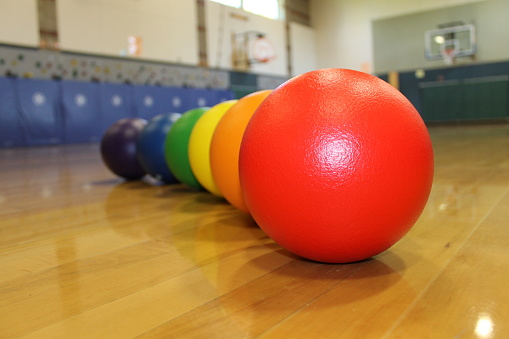 colorful dodgeballs on wood gym floor