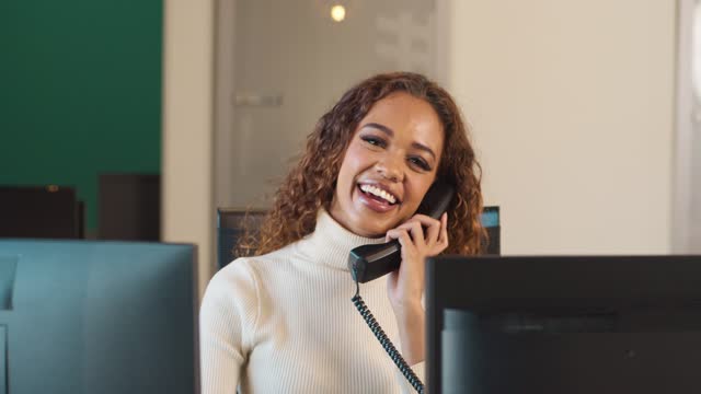 Pedestal shot of young woman answering the phone at reception front desk, hotel