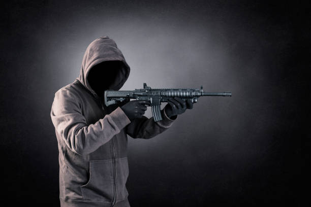 istock Hooded man with assault rifle over dark misty background 1501748090