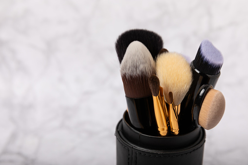 Cosmetic makeup brush on a white marble background. Professional makeup brushes in a case. Eyeshadow, blush, foundation and contouring brushes. Makeup tool. Visagiste. Place for text.Copy space