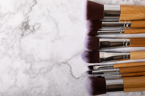 Cosmetic product for makeup. Makeup brushes on a white marble background. Creative fashion concept. Collection of cosmetic makeup brushes, top view, banner.Flat lay.